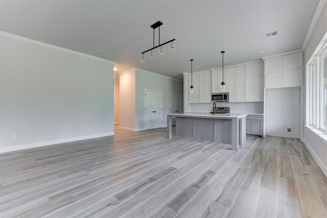 kitchen with crown molding, appliances with stainless steel finishes, tasteful backsplash, and light wood-type flooring