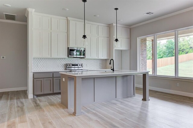 kitchen with appliances with stainless steel finishes, a sink, baseboards, tasteful backsplash, and ornamental molding