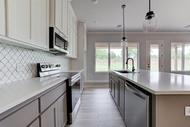 kitchen featuring a sink, light countertops, crown molding, and stainless steel appliances