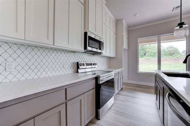 kitchen featuring visible vents, crown molding, light countertops, a sink, and appliances with stainless steel finishes