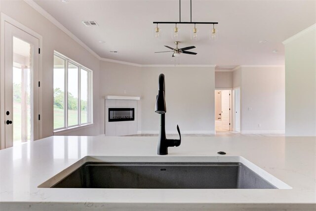 kitchen with ceiling fan, a sink, a tiled fireplace, open floor plan, and visible vents