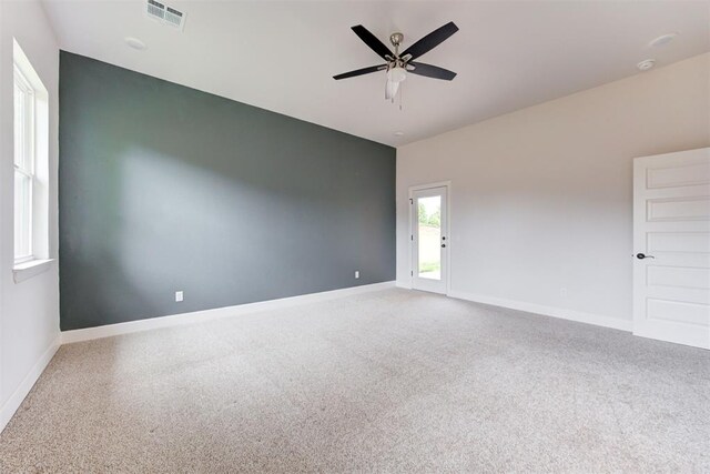 carpeted spare room with baseboards, a ceiling fan, and visible vents