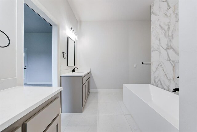 bathroom featuring vanity, baseboards, tile patterned floors, and a bathtub