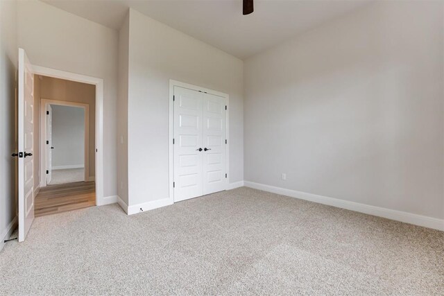 unfurnished bedroom with a ceiling fan, baseboards, carpet, and a closet