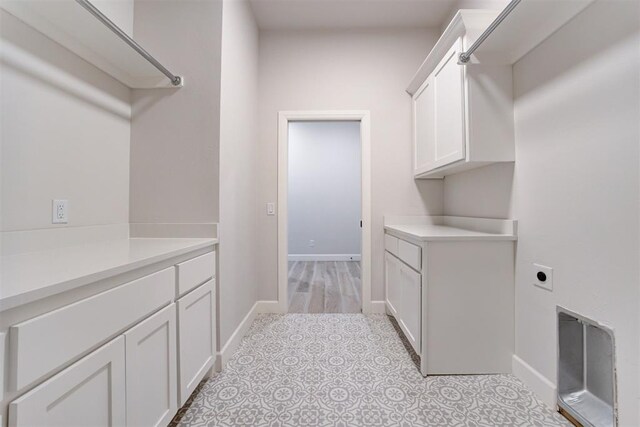 clothes washing area with cabinet space, hookup for an electric dryer, and baseboards