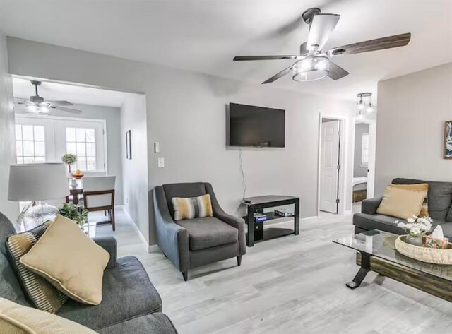 living room featuring a ceiling fan, baseboards, and light wood-style floors