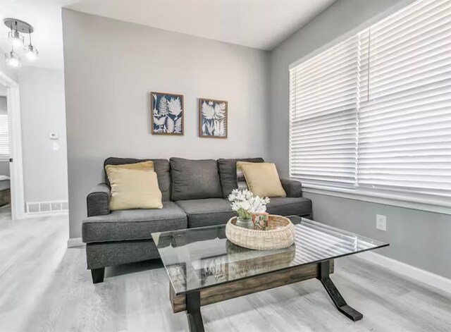 living room featuring baseboards, visible vents, and wood finished floors