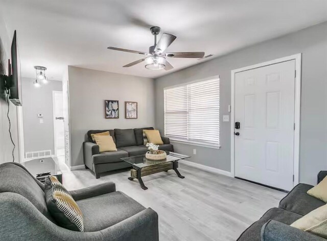 living area with baseboards, a ceiling fan, light wood-style flooring, and visible vents