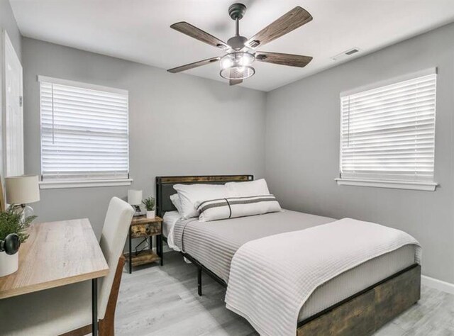 bedroom featuring baseboards, a ceiling fan, light wood finished floors, and visible vents