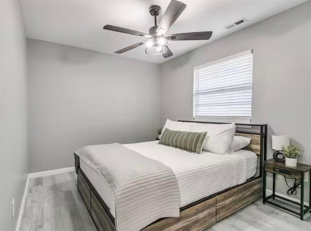 bedroom featuring baseboards, a ceiling fan, wood finished floors, and visible vents