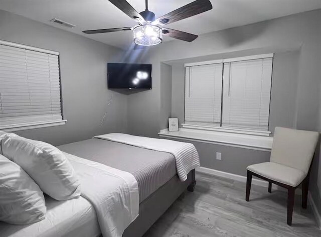 bedroom with baseboards, ceiling fan, wood finished floors, and visible vents