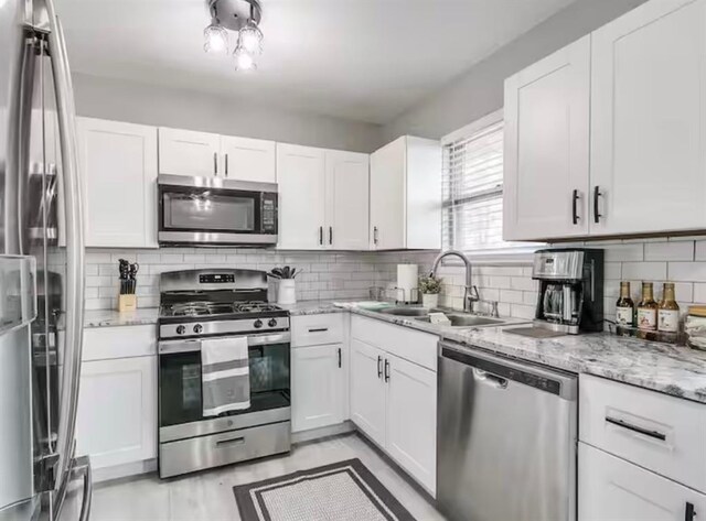 kitchen with a sink, appliances with stainless steel finishes, and white cabinetry