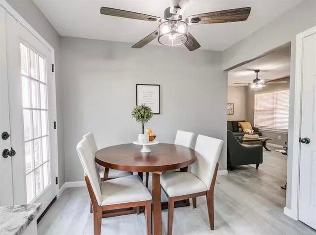 dining area featuring a ceiling fan, baseboards, and light wood finished floors