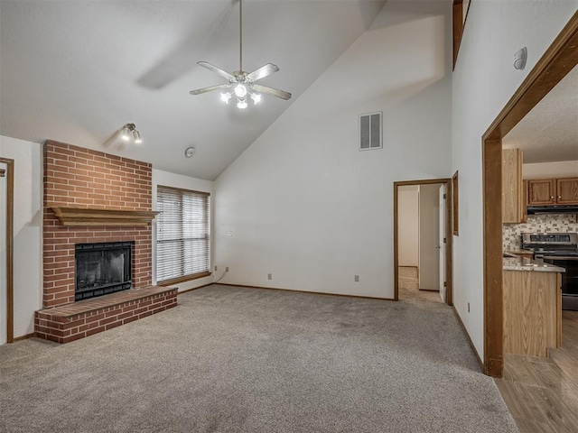 unfurnished living room with ceiling fan, light carpet, a fireplace, high vaulted ceiling, and visible vents