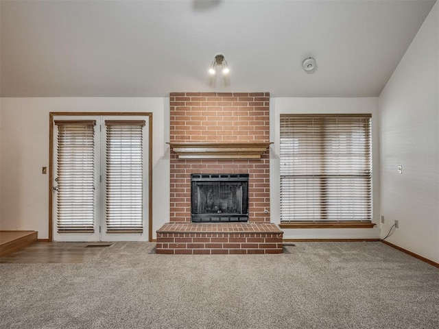 unfurnished living room featuring baseboards, plenty of natural light, a fireplace, and carpet flooring