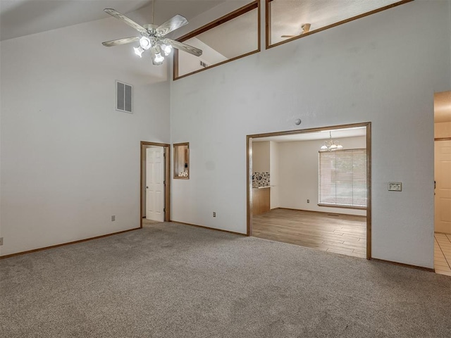 empty room with high vaulted ceiling, carpet, ceiling fan with notable chandelier, baseboards, and visible vents