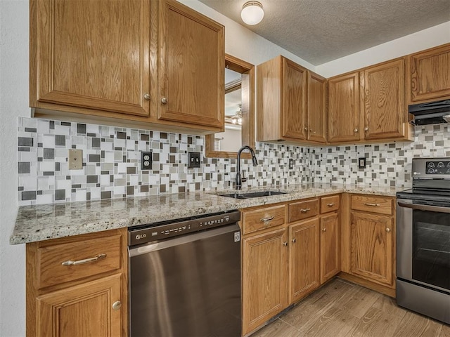 kitchen featuring a sink, decorative backsplash, light wood-style floors, and stainless steel appliances