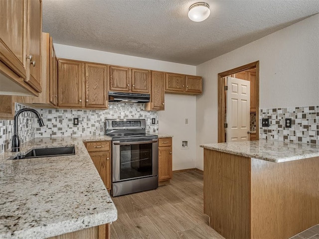 kitchen with brown cabinetry, a sink, exhaust hood, and stainless steel electric stove