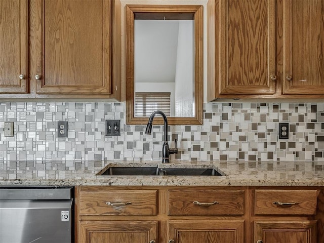 kitchen featuring a sink, decorative backsplash, stainless steel dishwasher, and brown cabinetry