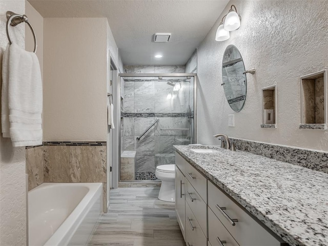 full bathroom featuring vanity, a stall shower, a bath, and toilet