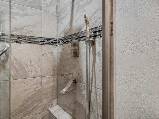 full bathroom with a textured wall and a tile shower