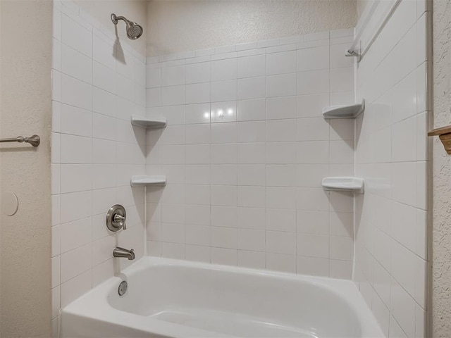 bathroom featuring a textured wall and shower / washtub combination