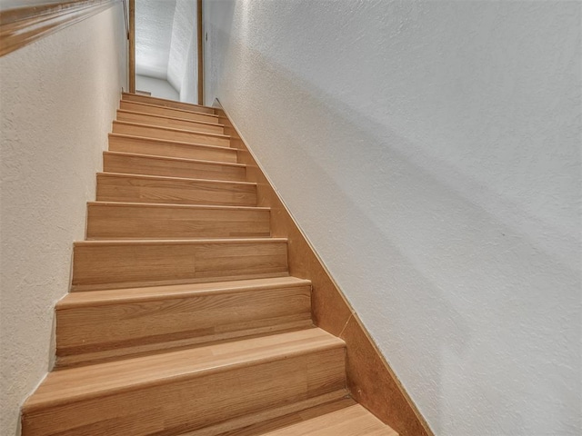 stairway featuring a textured wall