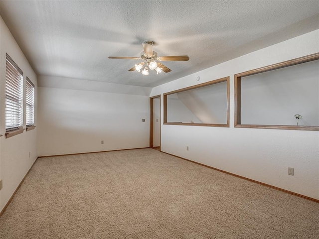 empty room featuring a textured ceiling, ceiling fan, light carpet, and baseboards