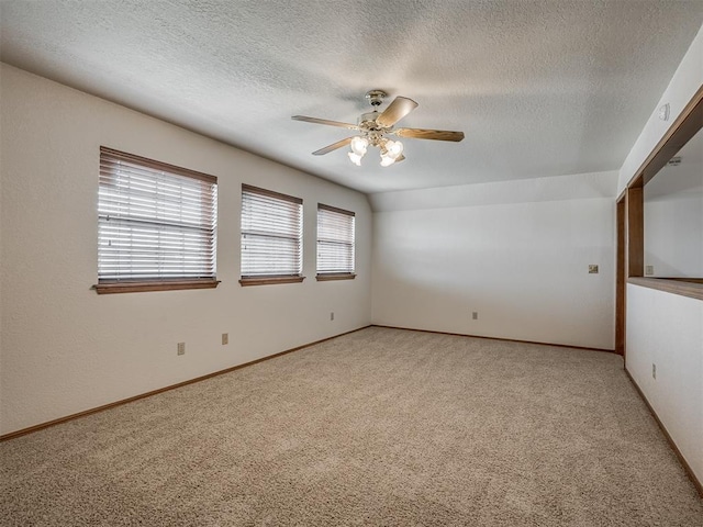 spare room with light colored carpet, a textured ceiling, ceiling fan, and baseboards