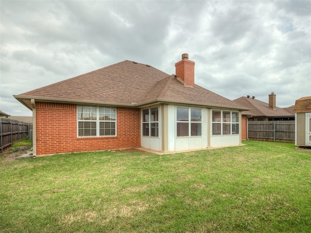 rear view of property featuring a yard, fence, a chimney, and roof with shingles