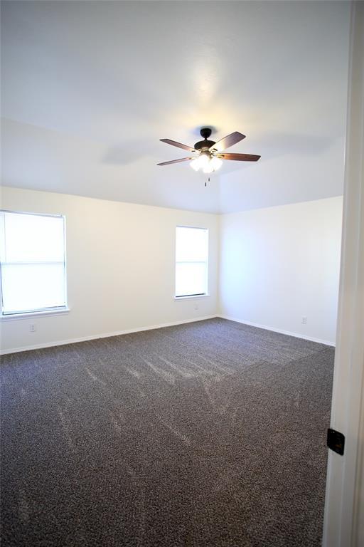 unfurnished room with dark carpet, baseboards, and ceiling fan