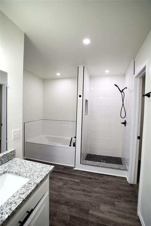 full bath with vanity, a shower stall, a bath, and wood finished floors