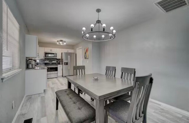 dining area with an inviting chandelier, baseboards, light wood finished floors, and visible vents