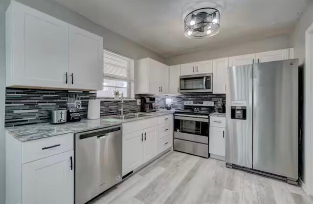 kitchen with a sink, white cabinets, and stainless steel appliances