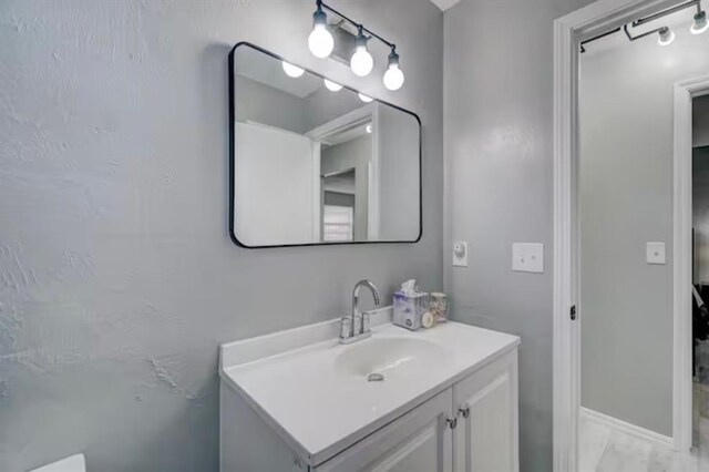 bathroom with vanity, baseboards, and marble finish floor