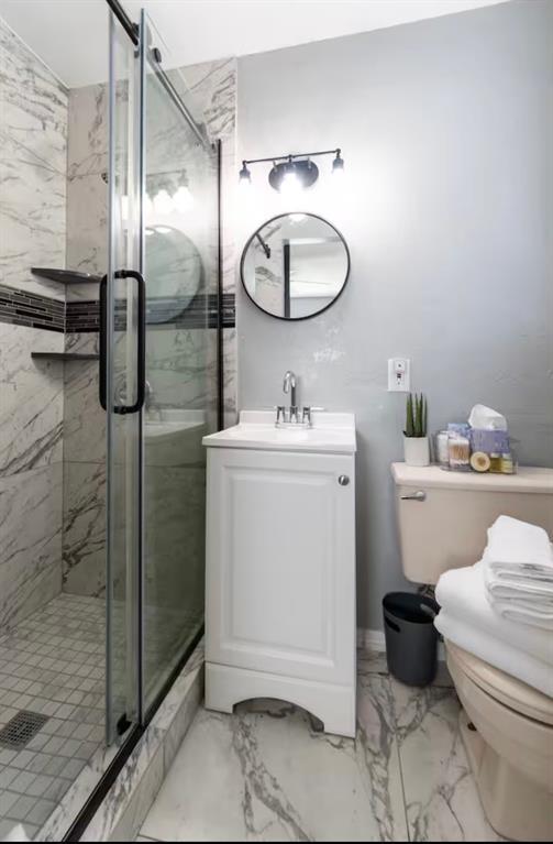 full bath with vanity, a stall shower, toilet, and marble finish floor