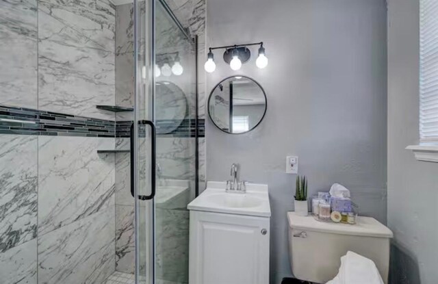 bathroom with a marble finish shower, vanity, and toilet