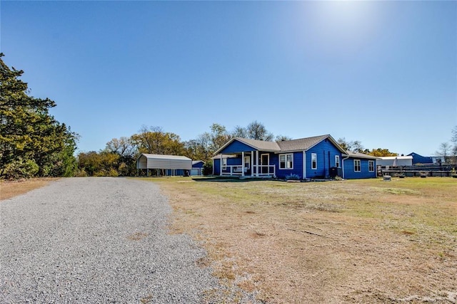 20318 State Highway 39, Purcell, OK 73080 - view of front of house with covered porch, a front yard, gravel driveway, and a carport