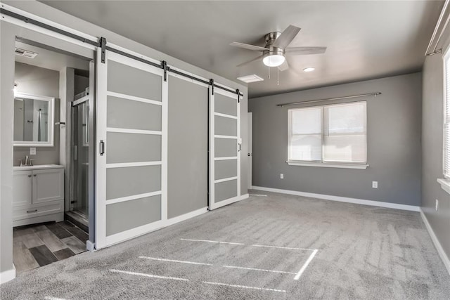 20318 State Highway 39, Purcell, OK 73080 - unfurnished bedroom featuring visible vents, a barn door, carpet floors, baseboards, and connected bathroom