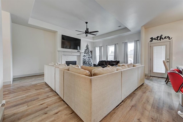 9600 Sultans Water Way, Yukon, OK 73099 - living area with a tray ceiling, light wood finished floors, a ceiling fan, a fireplace, and baseboards