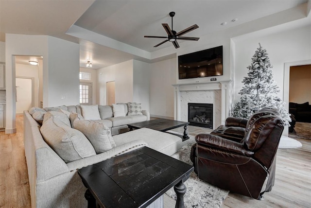 9600 Sultans Water Way, Yukon, OK 73099 - living room with a premium fireplace, light wood finished floors, a ceiling fan, and a tray ceiling