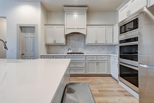 9600 Sultans Water Way, Yukon, OK 73099 - kitchen with appliances with stainless steel finishes, light wood finished floors, decorative backsplash, and light countertops