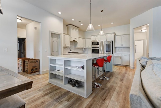 9600 Sultans Water Way, Yukon, OK 73099 - kitchen featuring stainless steel appliances, open shelves, light wood-style flooring, a breakfast bar area, and recessed lighting