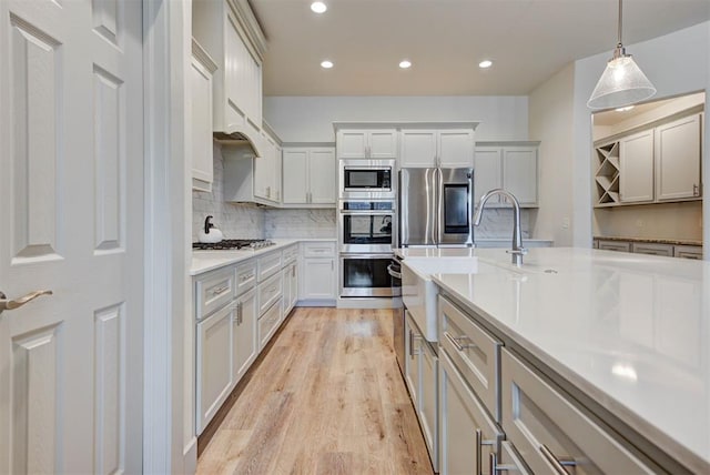 9600 Sultans Water Way, Yukon, OK 73099 - kitchen with appliances with stainless steel finishes, recessed lighting, a sink, light wood-style flooring, and hanging light fixtures