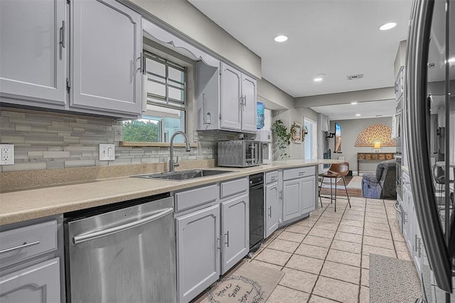 kitchen featuring a sink, appliances with stainless steel finishes, tasteful backsplash, and visible vents