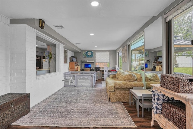 living room featuring dark wood-style flooring, visible vents, recessed lighting, and a fireplace