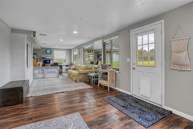 foyer entrance featuring visible vents, baseboards, a glass covered fireplace, and wood finished floors