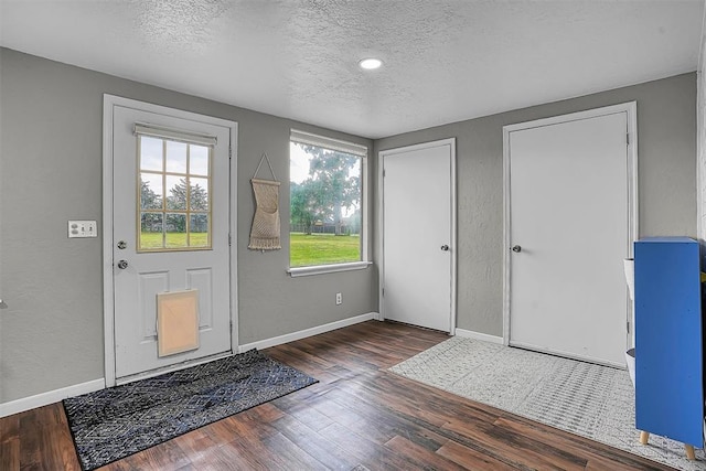 entrance foyer featuring baseboards, a textured wall, a textured ceiling, and wood finished floors