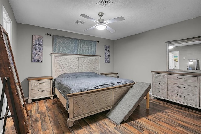bedroom with a ceiling fan, a textured ceiling, visible vents, and dark wood finished floors