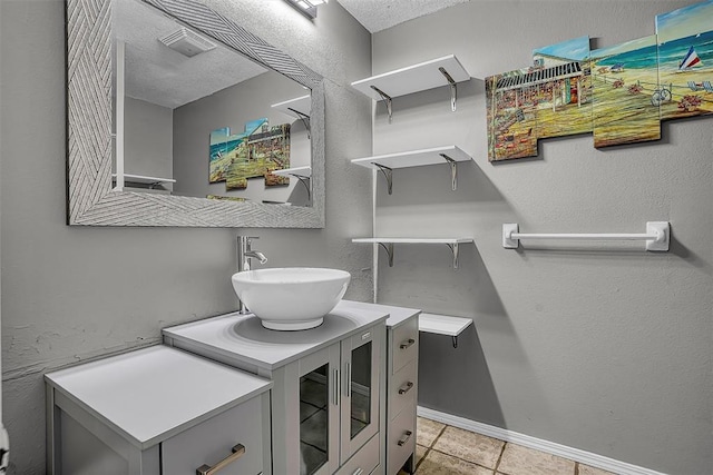 laundry room featuring baseboards, a sink, a textured ceiling, and light tile patterned floors